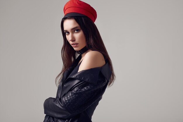 Mode femme brune vêtue d'une veste en cuir et d'un chapeau rouge