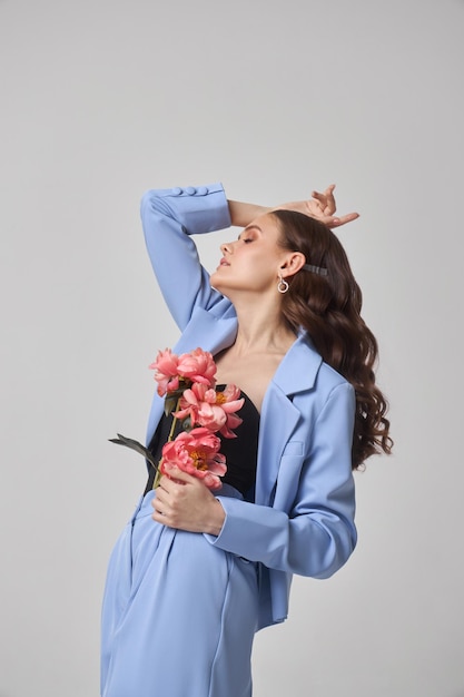 Mode femme en costume bleu avec des fleurs roses beauté visage portrait Art studio portrait d'une jeune femme sur un fond blanc maquillage rose