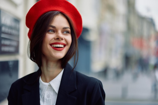 Photo mode femme sourire printemps marchant dans la ville dans des vêtements élégants avec des lèvres rouges et béret rouge voyage cinématographique couleur rétro style vintage mode de vie urbaine