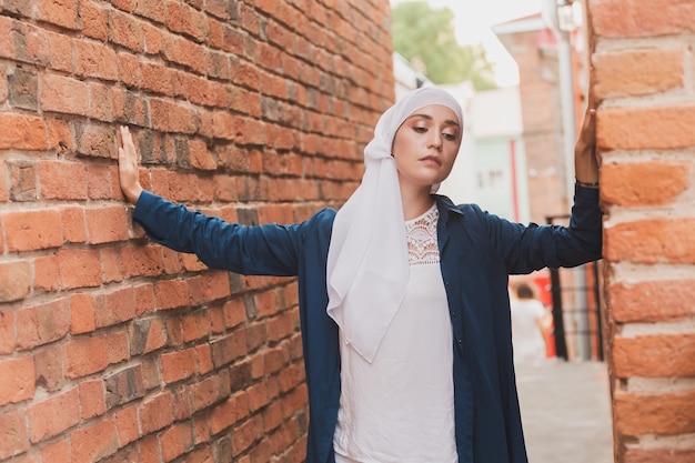 Mode fille musulmane moderne avec hijab. Beau modèle féminin musulman portant le hijab et tenue décontractée posant sur fond urbain