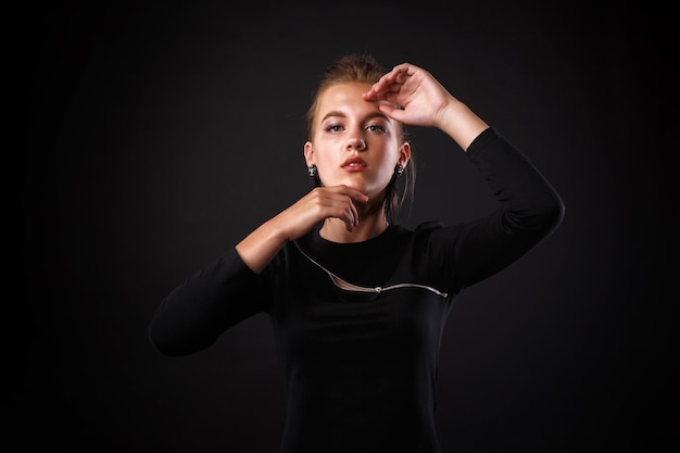 Mode glamour portrait d'une jeune fille en robe noire sur fond sombre coiffure élégante maquillage lumineux et couleur des lèvres