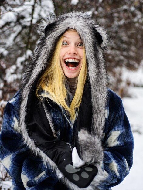 Mode hivernale femme heureuse en vêtements chauds avec boule de neige fille souriante en mites manteau à carreaux chaud