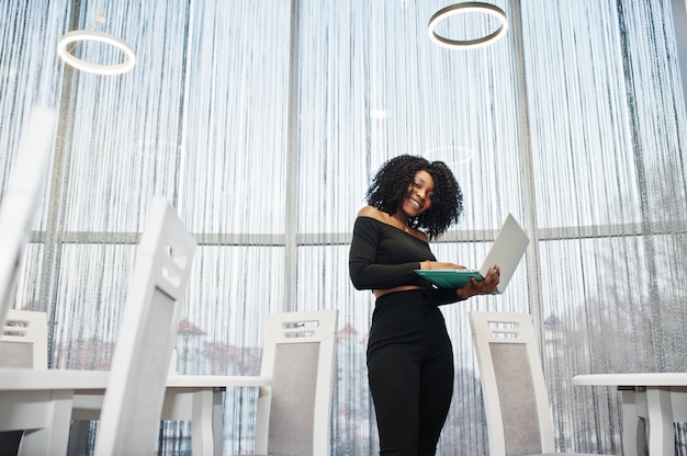 À la mode jeune belle femme d'affaires avec une coiffure afro à l'aide d'un ordinateur portable