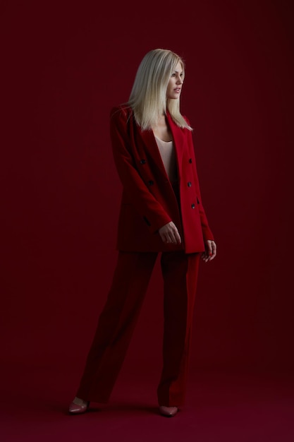 Mode jeune femme en costume rouge fond rouge