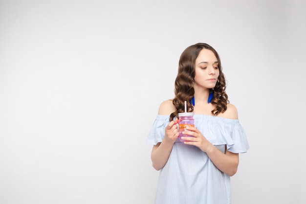 À la mode jeune femme avec cotail dans ses mains sur fond