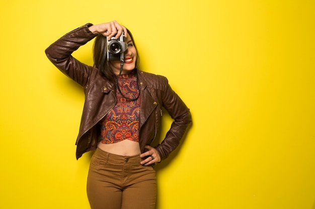 Photo mode jeune femme fait la photo avec un vieil appareil photo sur mur jaune