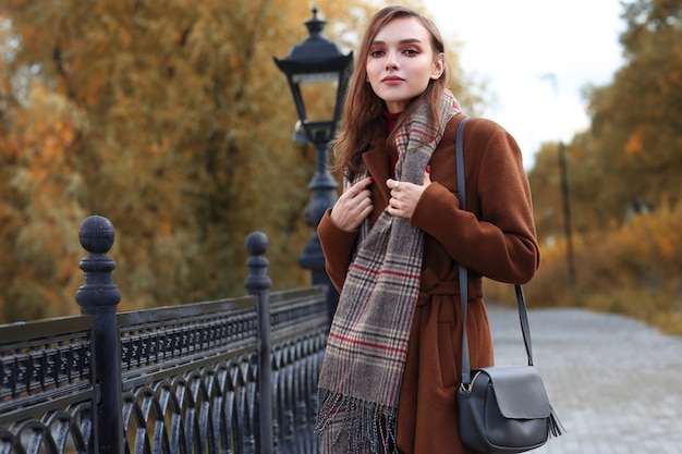 Mode jeune femme en plein air portant manteau, écharpe et sac à main