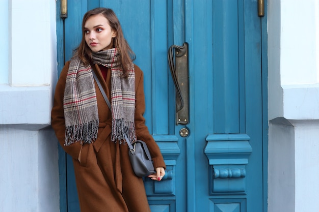 Mode jeune femme en plein air portant manteau, écharpe et sac à main