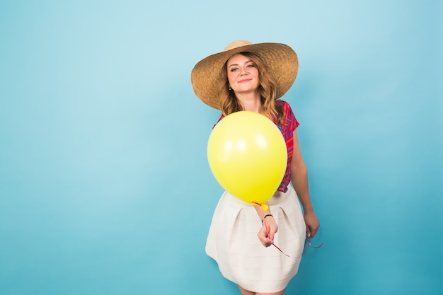 Mode jeune femme souriante avec ballon à air jaune sur fond bleu coloré avec fond.