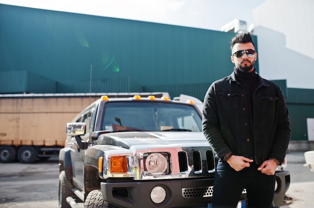 À la mode jeune homme barbu posant à l'extérieur avec une grosse voiture