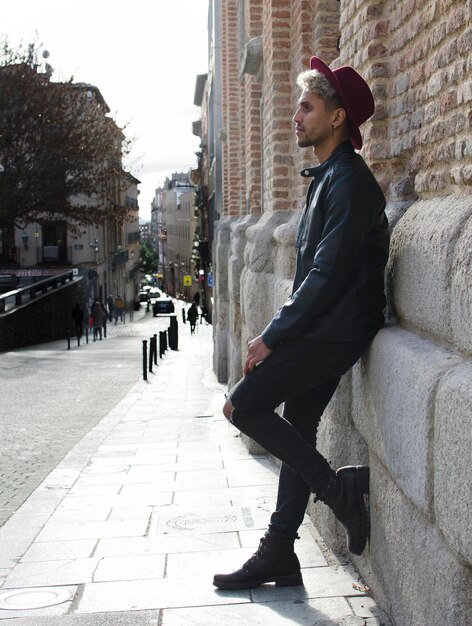 Mode jeune mannequin avec veste en cuir et chapeau rouge dans la rue