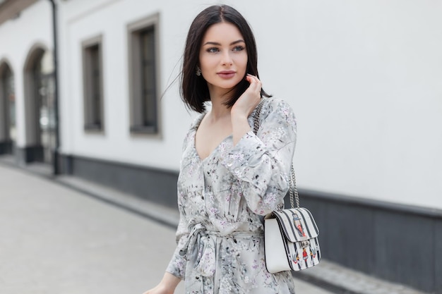 Mode jolie beauté fille avec coiffure short au printemps fleurs élégantes robe avec sac à main à la mode promenades dans la ville