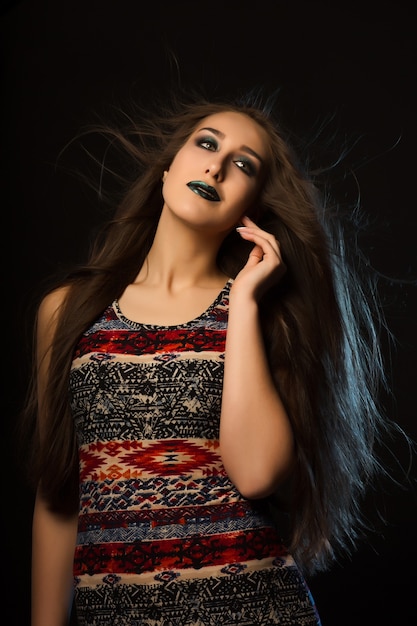 Mode portrait d'une femme bronzée élégante avec des cheveux volants et du maquillage artistique