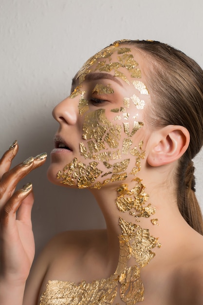 Mode portrait d'une femme brune glamour avec un maquillage créatif de feuille d'or