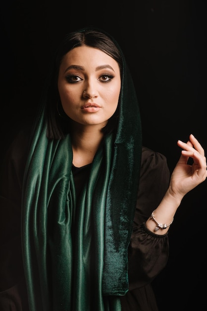 Mode portrait de femme en foulard vert ou hidjab posant sur fond sombre