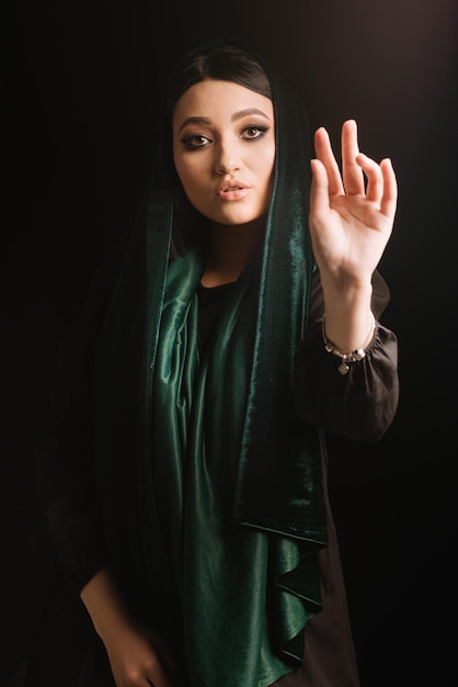 Mode portrait de femme en foulard vert ou hidjab posant sur fond sombre