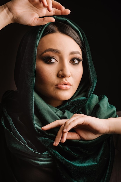 Mode portrait de femme en foulard vert ou hidjab posant sur fond sombre