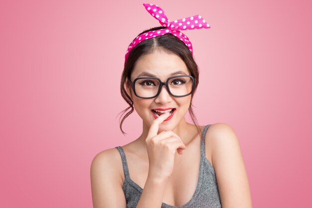 Mode portrait d'une fille asiatique avec des lunettes de soleil debout sur fond rose.