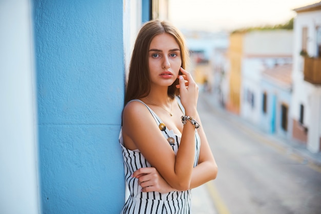 Mode portrait de jeune femme élégante posant contre le mur bleu.