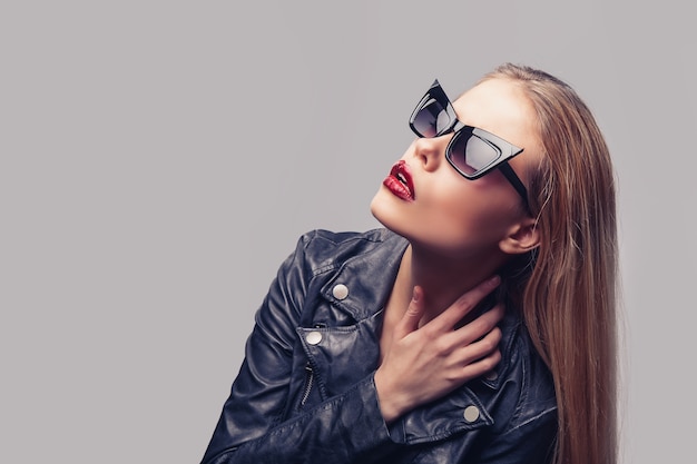 Mode portrait de jeune femme élégante en veste de cuir noir, lunettes de soleil.