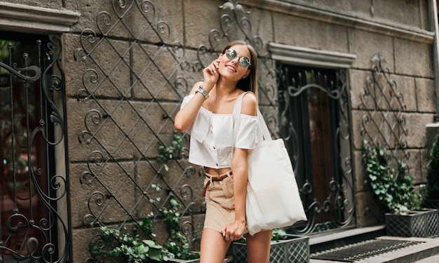 Mode de rue. Femme élégante à la mode dans des vêtements à la mode et des lunettes de soleil posant à l'extérieur contre l'architecture ancienne