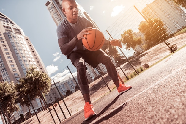 Mode de vie actif. Beau jeune homme jouant au basket-ball tout en développant ses compétences