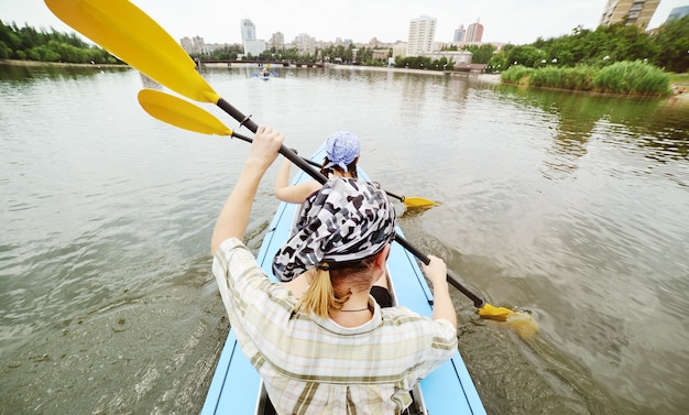 Mode de vie actif - nagez dans un kayak sur la rivière contre la surface de la ville