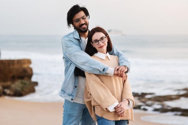 Mode de vie actif et week-end heureux jeune indien étreignant une femme caucasienne profiter du temps libre de l'océan