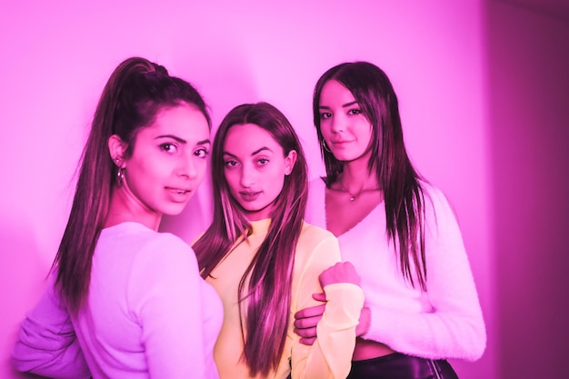 Mode de vie d'amis faisant la fête dans une boîte de nuit avec des néons roses portrait de jeunes belles femmes caucasiennes regardant la caméra