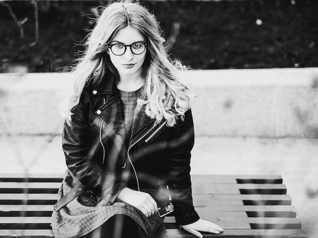 Mode de vie et concept de personnes fille blonde assise sur un banc photo noir et blanc de la ville d'été