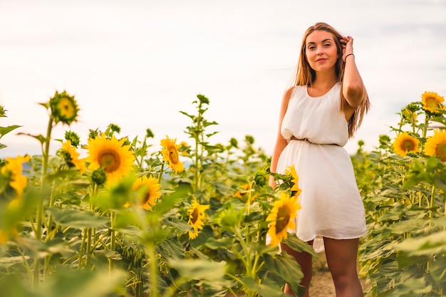 Mode de vie dans la ville de Pampelune, une jeune blonde en robe connaissant un champ de tournesols