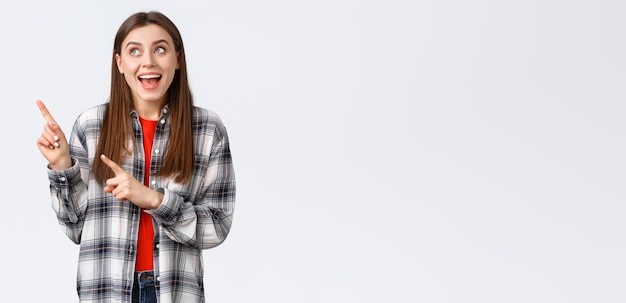 Mode de vie différentes émotions concept d'activités de loisirs Excité femme heureuse en chemise à carreaux pointant du doigt le coin supérieur gauche et souriant amusé de faire le choix trouvé ce qu'elle recherche