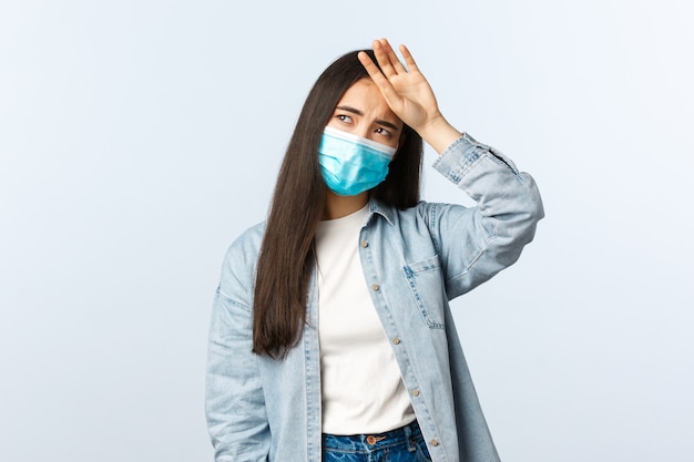 Mode de vie à distance sociale, vie quotidienne pandémique covid-19 et concept de loisirs. Une fille asiatique en médecine se sentant malade, touchant le front, ayant de la fièvre et de la fatigue, détournant le regard en détresse.