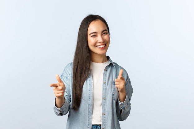 Mode de vie, émotions des gens et concept de beauté. Une femme asiatique sympathique et effrontée félicite un ami, loue un bon travail ou dit bien plaqué en pointant l'appareil photo et souriant