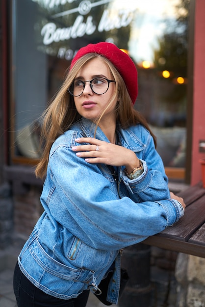 Mode de vie ensoleillé d'été mode portrait de jeune femme élégante hipster marchant dans la rue, portant une tenue à la mode mignonne avec chapeau rouge