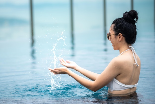 Mode de vie d'une femme asiatique avec de l'eau d'été, jeune fille portant des articles de natation pour nager dans une piscine d'eau, temps de vacances en vacances pour se détendre et se réjouir d'un plaisir sain