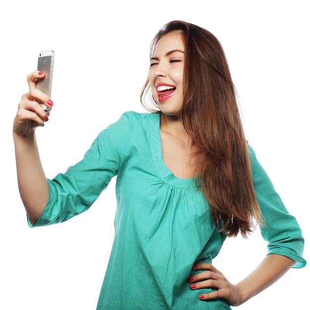 Mode de vie des gens et concept de tehnologie jolie adolescente portant une chemise verte prenant des selfies avec son téléphone intelligent isolé sur blanc