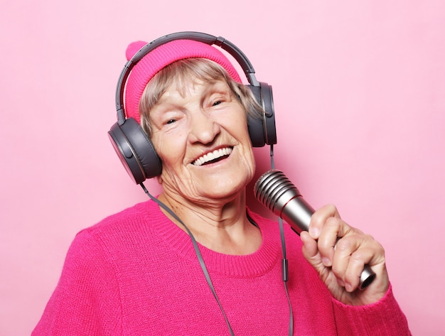 Mode de vie et les gens: vieille dame drôle écouter de la musique avec des écouteurs et chanter avec micro
