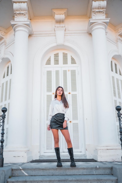 Mode de vie d'une jeune brune en jupe et chemise en cuir noir dans les escaliers