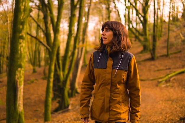 Mode de vie d'une jeune femme en veste jaune marchant à reculons le long d'une forêt