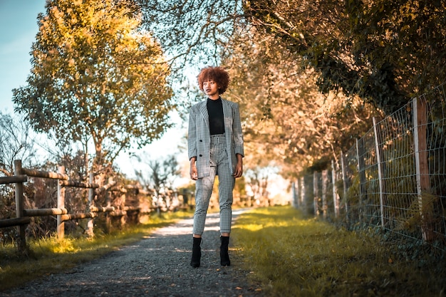 Mode de vie, une jeune fille dominicaine aux cheveux afro marchant sur le chemin dans un parc en automne