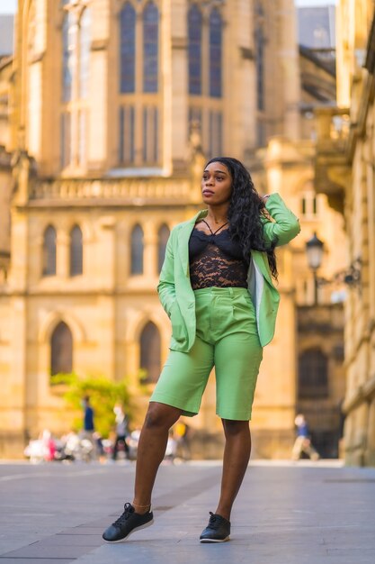 Mode de vie d'une jeune fille d'ethnie noire africaine avec un beau costume vert. Visite de la ville en marchant à côté d'une cathédrale