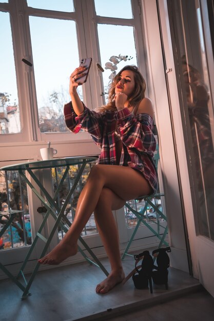 Mode de vie d'un jeune petit-déjeuner blonde prenant son petit-déjeuner à côté de la vente de sa maison. Vêtu de sous-vêtements et pyjama, effectuant un selfie