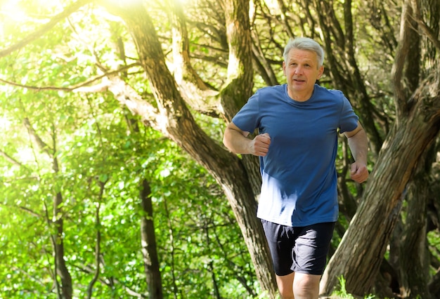 Mode de vie de jogging - senior homme séduisant qui court dans le parc d'été