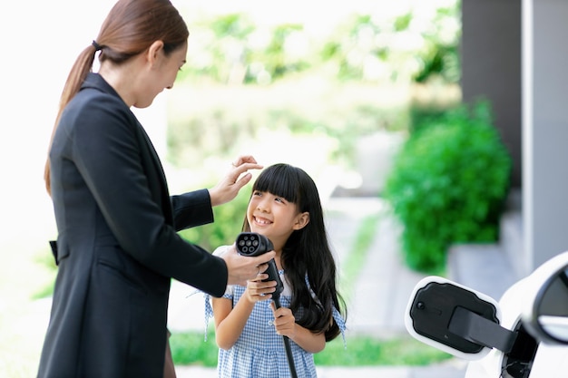 Mode de vie progressif de la mère et de la fille avec voiture EV et station de charge