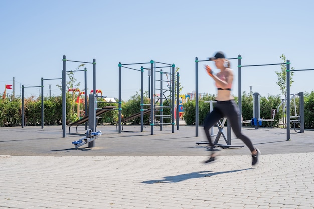 Photo mode de vie sain et actif. sport et remise en forme. femme heureuse en vêtements de sport s'entrainant sur le terrain de sport en journée d'été ensoleillée en cours d'exécution