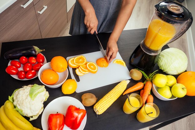 Mode De Vie Sain Et écologique. Femme Indienne Heureuse Avec Son Mari Faisant Un Smoothie à L'orange Dans Une Grande Cuisine.