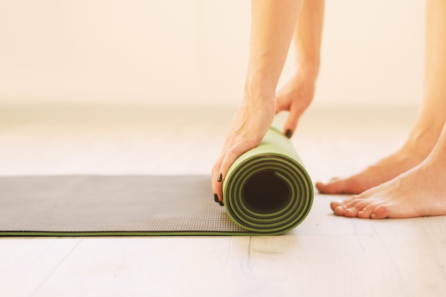 Mode de vie sain - Fille utilise un tapis de yoga - Rouleau de tapis de sport vue latérale rapprochée
