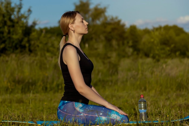 Mode de vie sain Jeune femme médite sur un tapis de yoga au coucher du soleil Entraînement et entraînement à l'air frais