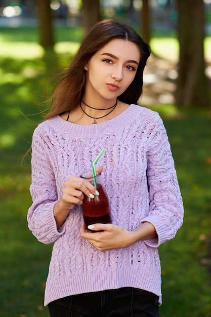 Mode de vie sain. Jolie jeune femme avec un pot de smoothie à la betterave fraîche, sur fond de nature verdoyante.